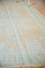 Distressed pile texture of the Oushak rug, featuring faded beige and mint green tones.