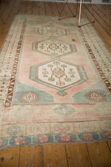 Artfully distressed Oushak runner with faded sea foam green and pale blush border patterns.
