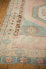Distressed Oushak runner's faded rose, sea foam green borders with subtle geometric motifs.