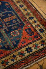 Northwest Persian rug detail with cherry red spandrel, navy field, and worn beige border.