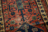 Antique Northwest Persian rug's cherry red field, navy geometric floral motifs, and low pile.