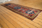 Corner of antique Northwest Persian runner showing cherry red field, low pile, and secured edges.