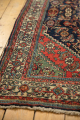 Fringed corner of vintage Engelas rug displaying brick red, navy, oxidized green Herati-like patterns.
