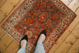 Overhead view showing the scale of an antique Malayer rug's warm red and brown floral pattern.