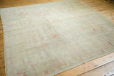 Distressed vintage Oushak rug, showing soft pale terra cotta motifs on a beige field.