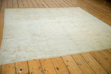 Distressed Oushak rug with subtle pattern in pale silver, beige, and terra cotta.