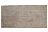 Vintage distressed Oushak runner with a faded blush stepped medallion on a beige field.