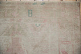 Even wear on distressed Oushak runner pile, with pale blush, sand, and muted teal motifs.