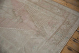 Distressed vintage Oushak rug runner detail, showing faded pale blush, beige, and geometric border.