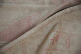 Distressed Oushak rug pile in blush and beige, featuring a pale blue stepped contour.