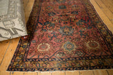 Detailed corner of antique Lilihan rug, revealing tattered edge, secured fringe, raspberry field, and blue palmette motifs.