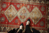 Antique Caucasian rug with cherry red field, diamond medallions, and visible foundation wear.
