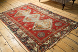 Antique Caucasian rug corner showing geometric pawn motif border and faded cherry red field.