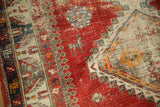 Cherry red field of an antique Caucasian rug featuring a deer motif and rich, textured surface.
