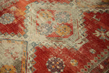 Close-up of worn cherry red and ivory geometric patterns on an antique Caucasian rug.