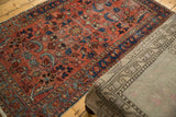 Vintage Lilihan rug side, showing raspberry red floral field, blue border, and even wear.