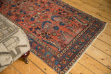 Persian Lilihan rug corner, showing raspberry red floral field, sky blue border, and visible pile wear.