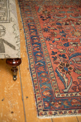 Vintage Lilihan rug: detailed blue border, raspberry red field with floral blossoms and contoured leaves.