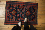 Upper corner of antique Lilihan rug, intricate red and blue florals, with a mostly secure side.