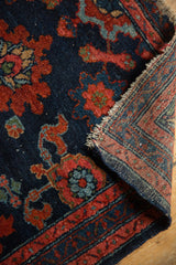 Early 20th century Persian Lilihan rug detail: navy, red floral pile, wear, and woven foundation.