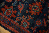 Softened pile and intricate madder root red floral motifs on the antique Lilihan rug's navy field and border.
