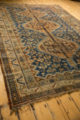 Vintage Kamseh rug's tattered end and worn fringe, with navy, copper, and brown geometric borders.