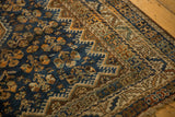 Close-up of the vintage Kamseh carpet's traditional geometric navy and copper border with tattered fringe.