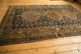 Vintage Kamseh carpet with intricate geometric border and navy field of copper-orange floral blossoms.