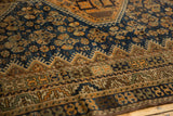 Vintage Kamseh rug detail: worn navy blue field, copper floral motifs, and geometric border.