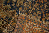 Close-up of Kamseh rug's tattered fringe and dark navy, copper geometric patterns.