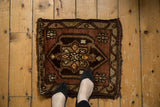 Vintage Oushak mat corner with secured dark brown fringe and copper floral motifs.