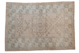 Muted beige and mint green distressed Oushak rug with geometric medallion and wide border.