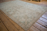 Distressed vintage Oushak rug with muted beige and dusty mint geometric patterns.