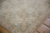 Distressed Oushak rug pile texture with geometric beige and dusty mint patterns.