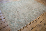 Distressed Oushak rug corner featuring wide banded geometric border in pale sand and dusty mint.