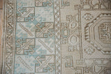 Geometric patterns and distressed texture of this Oushak rug in beige, mint, and pale blue.