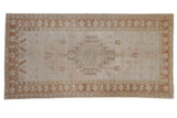Vintage distressed Oushak rug with a stepped diamond medallion in a palette of pale blush, copper, and beige.