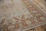 A vintage Oushak rug corner showing its copper floral border and evenly worn, low-pile texture.