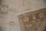 A folded corner shows the hand-knotted foundation and secured edge of the vintage Oushak rug.