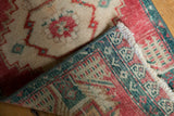 Close-up of distressed vintage Oushak rug's worn pile, red and aqua border, and hand-knotted reverse.