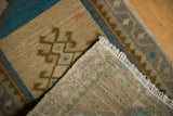 Worn pile texture, ivory fringe, and visible hand-knotted back of an Oushak rug.