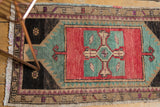 Distressed vintage Oushak rug corner with fringe, showing rose blush, aqua blue, and charcoal details.