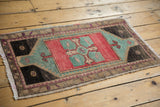 Distressed Oushak rug corner showing low pile texture, woven fringe, and colorful tribal motifs.