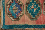 Two nuanced gul medallions on abrashed blush field with aqua border of a distressed Oushak rug.