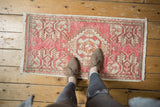 Distressed vintage Oushak rug mat with blush, ivory, and faded geometric plant motifs.
