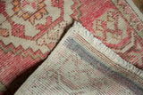Distressed blush Oushak rug with hand-knotted pile, secured fringe, and woven foundation.