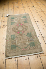 Vintage distressed Oushak rug's side edge with low pile texture, green plant motif, pink accents.