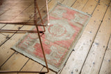 Distressed texture on vintage Oushak rug mat with blush border and faint plant motif.