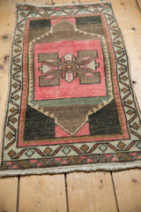 Distressed Oushak rug corner, showing worn pile texture and pink, charcoal, ivory tones.