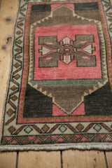 Distressed vintage Oushak rug displaying pink quatrefoil motif and worn pile texture.